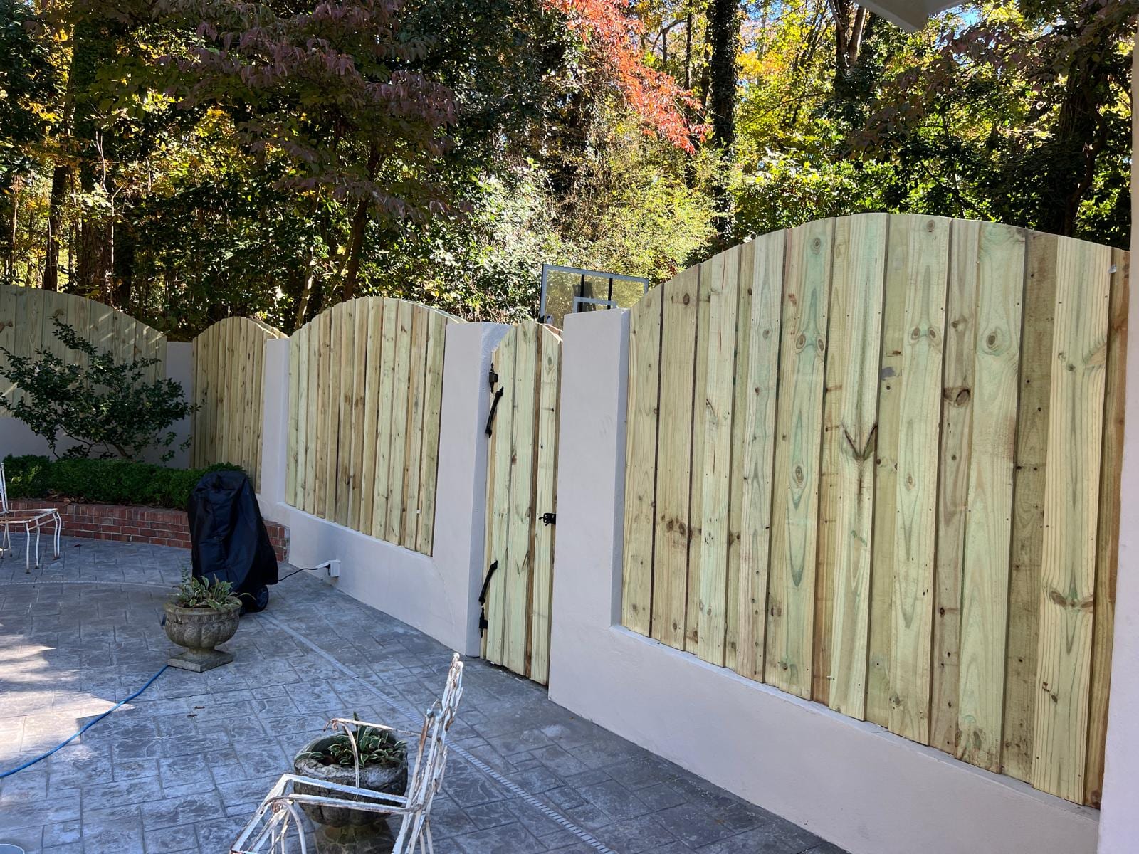 Custom arched-top wood privacy fence and gate built over a masonry courtyard wall
